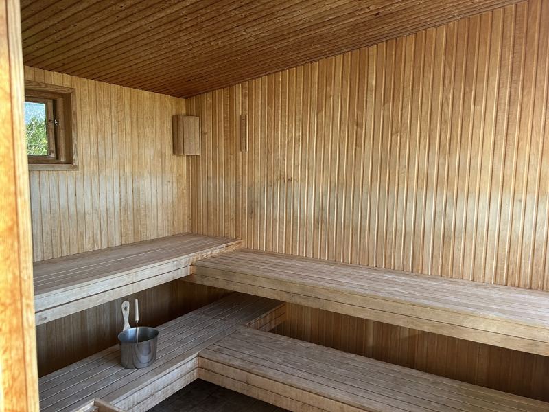 Stanza d'ina sauna da lain cun bancs e sadella per l'aua